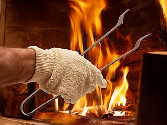 Personne en combinaison de protection utilisant un extincteur rouge pour combattre un incendie avec flammes intenses en arrière-plan